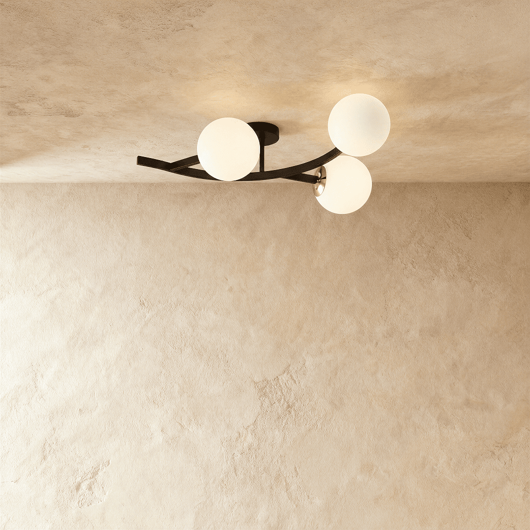 Clérachic three-globe ceiling light on a curved black arm with opal white glass globes, lit against plaster.