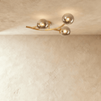 Clérachic three-globe ceiling light on a curved gold arm with smoked glass globes, each lit by a bare bulb.