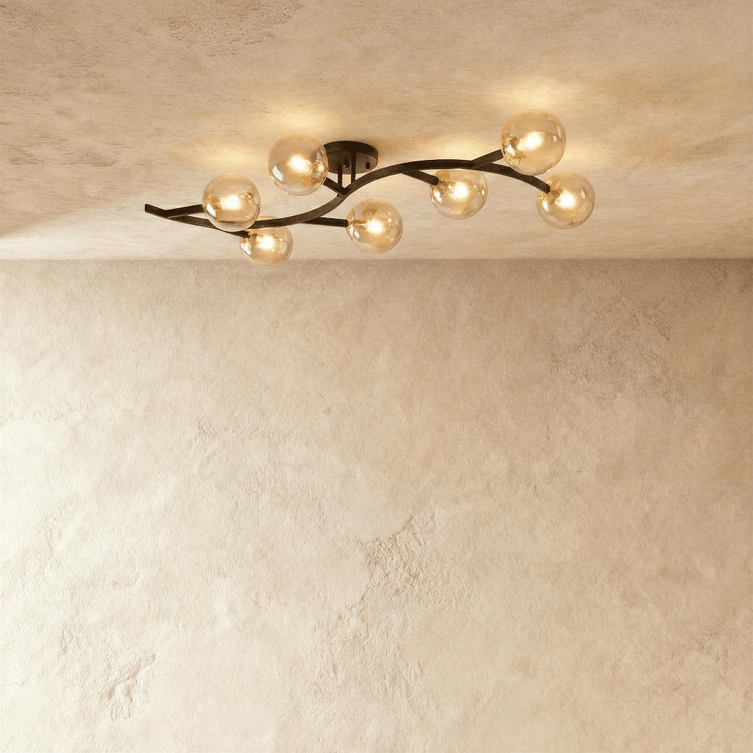 Clérachic seven-globe ceiling light on a sweeping black arm with amber-tinted glass globes, lit on plaster.