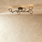 Clérachic five-globe ceiling light on a sweeping black arm with smoked glass globes, lit against plaster.