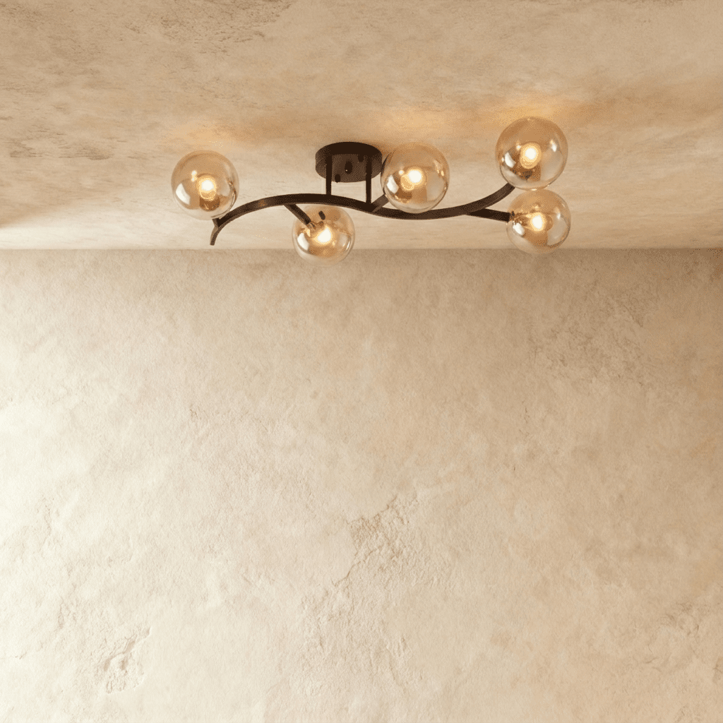 Clérachic five-globe ceiling light on a sweeping black arm with amber-tinted glass globes lit on plaster.