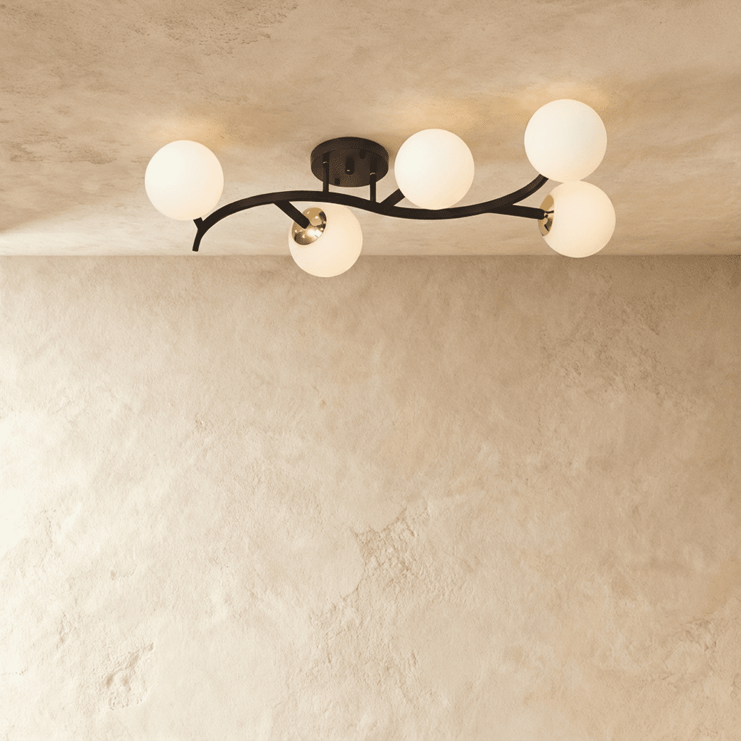 Clérachic five-globe ceiling light with a sweeping black arm, nickel-toned joints and opal white globes, lit.