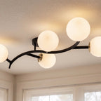 Close view of a Clérachic black-armed ceiling light with opal white globes, brass joints and a curved arm.
