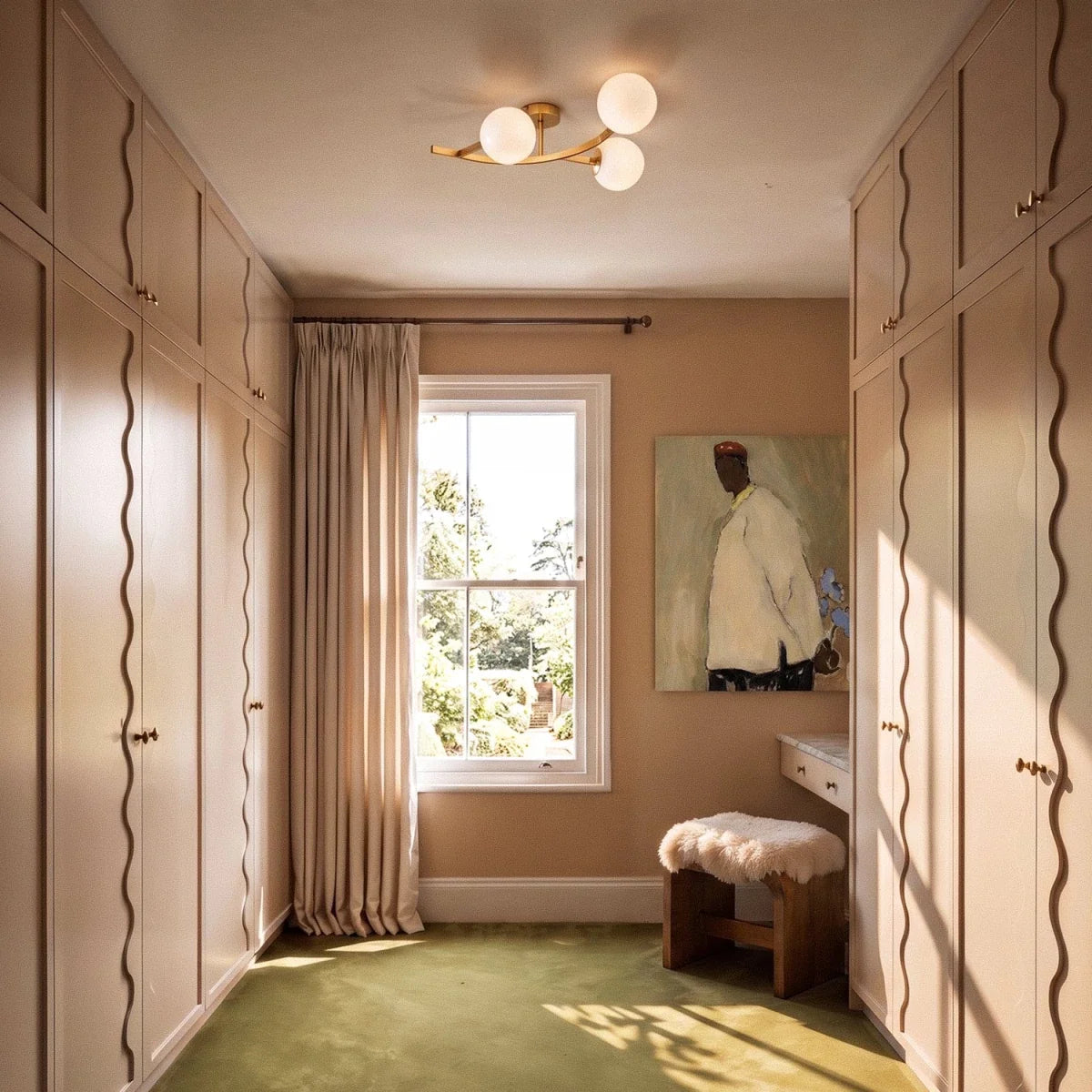 Clérachic gold-armed three-globe ceiling light with opal white globes in a dressing room with fitted wardrobes.