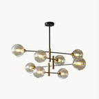 Eight-head Clérachic chandelier with amber glass globes on black arms and brass-toned stems, hung from a black rod on a white backdrop.
