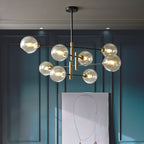 Lit Clérachic chandelier with amber glass globes, hung in a teal panelled room in front of a line drawing of a face.