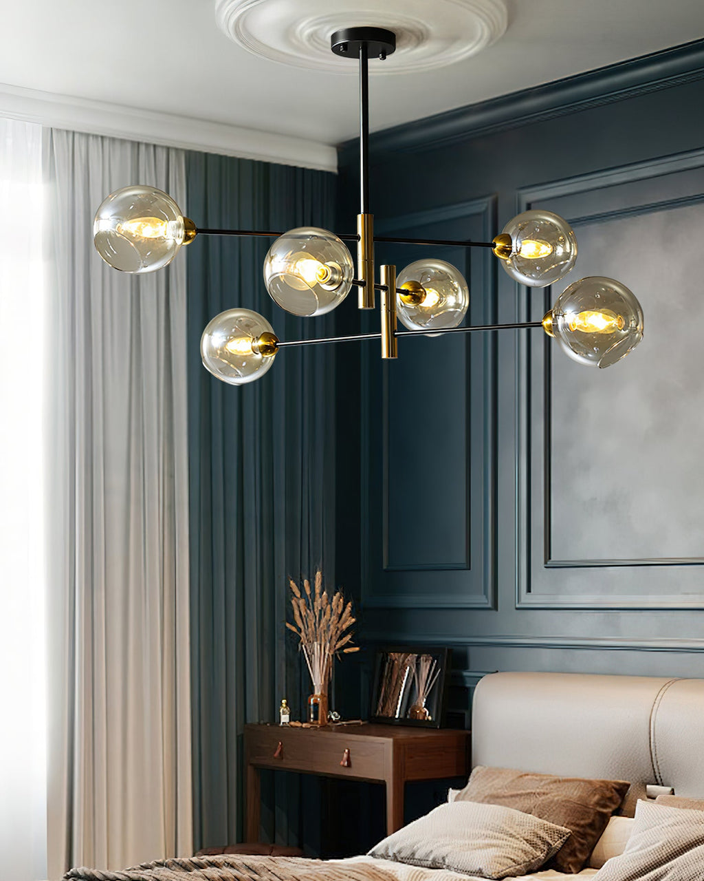 Clérachic chandelier with amber globes in a bedroom corner, beside sheer curtains and a teal panelled wall with a small timber desk.