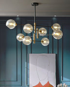 Clérachic chandelier with amber globes glowing in a teal panelled room, above a large line drawing leaning against the wall.