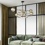 Clérachic chandelier with amber globes in a room with a black-framed glass partition, olive curtains and a sage green sofa.