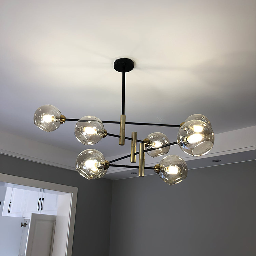 Eight-head Clérachic chandelier with amber globes lit on a white ceiling, in a room with grey walls and a white doorway.