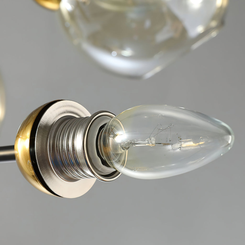 Close view of a clear bulb in a brass-toned socket on this Clérachic chandelier, with a glass globe shade above it.