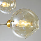 Close view of one amber glass globe on this Clérachic chandelier, with the lit bulb visible through the open side of the shade.