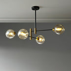 Four-head Clérachic chandelier with amber globes lit on staggered black arms, below a grey ceiling with a plain cornice.