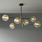 Six-head Clérachic chandelier with amber globes lit on black arms with brass-toned stems, below a grey ceiling.