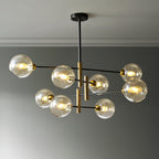 Eight-head Clérachic chandelier with amber globes, all lit, hanging from a black ceiling plate against a grey wall.