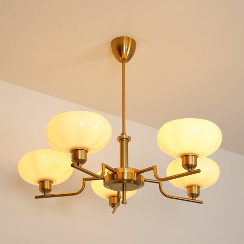 Clérachic five-head copper chandelier lit warm, its five opal globes glowing against a beige evening ceiling.