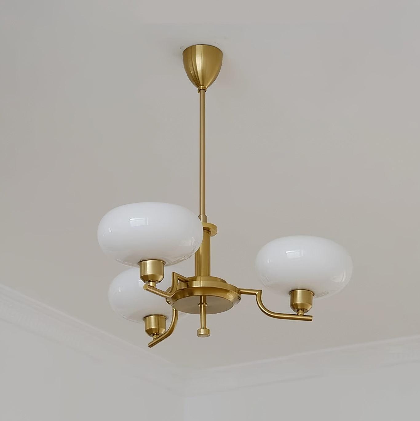Clérachic three-head copper chandelier with white opal globes, seen at an angle against a plain ceiling corner.