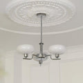 The Clérachic three-head chrome chandelier hangs below a moulded ceiling rose in a panelled white room.