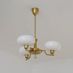 Angled view of the Clérachic three-head copper chandelier, showing the curved arms and three white globes.