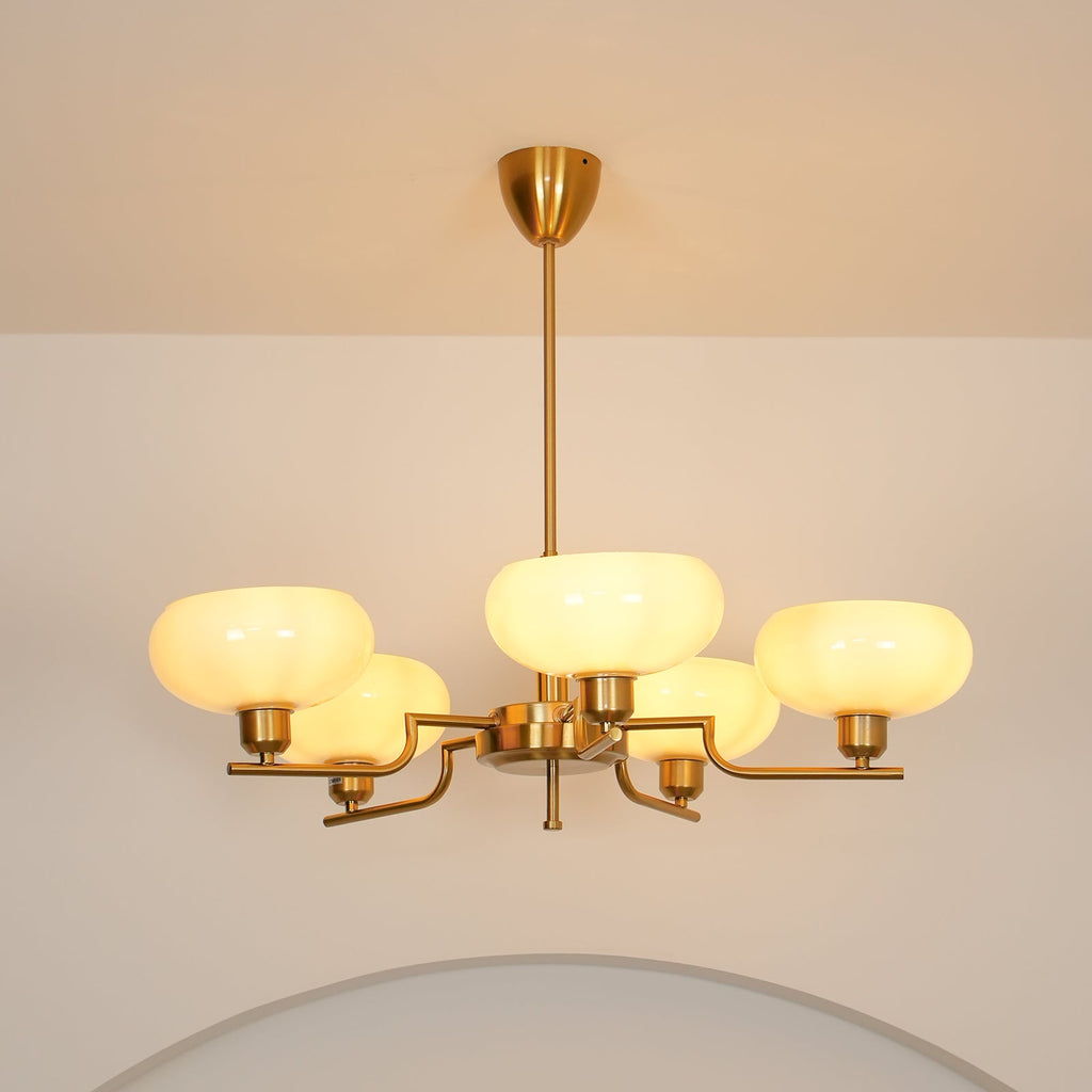 Clérachic five-head copper chandelier switched on, its opal globes casting a warm glow above a pale archway.