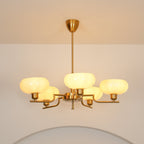 Clérachic five-head copper chandelier switched on, its opal globes casting a warm glow above a pale archway.