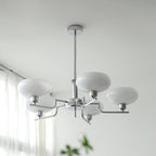 Clérachic five-head chrome chandelier with white glass globes, viewed from below in a bright living room.