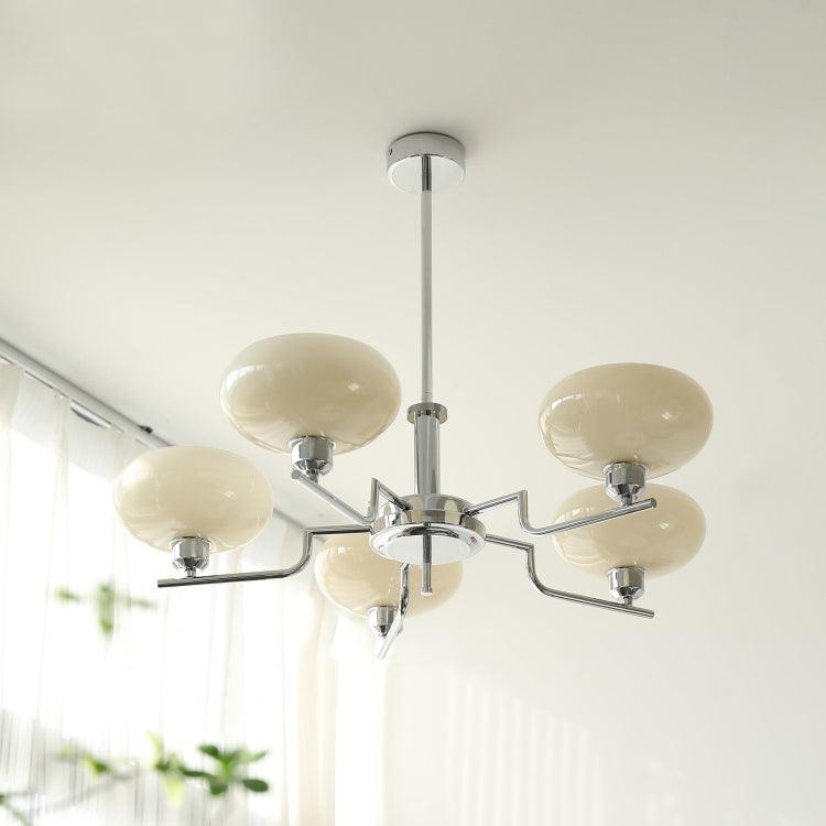 Clérachic five-head chrome chandelier in cream glass, hung in a light-filled room beside sheer curtains.