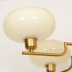 Close-up of a Clérachic cream glass globe on the copper cup fitting, a second shade behind it.