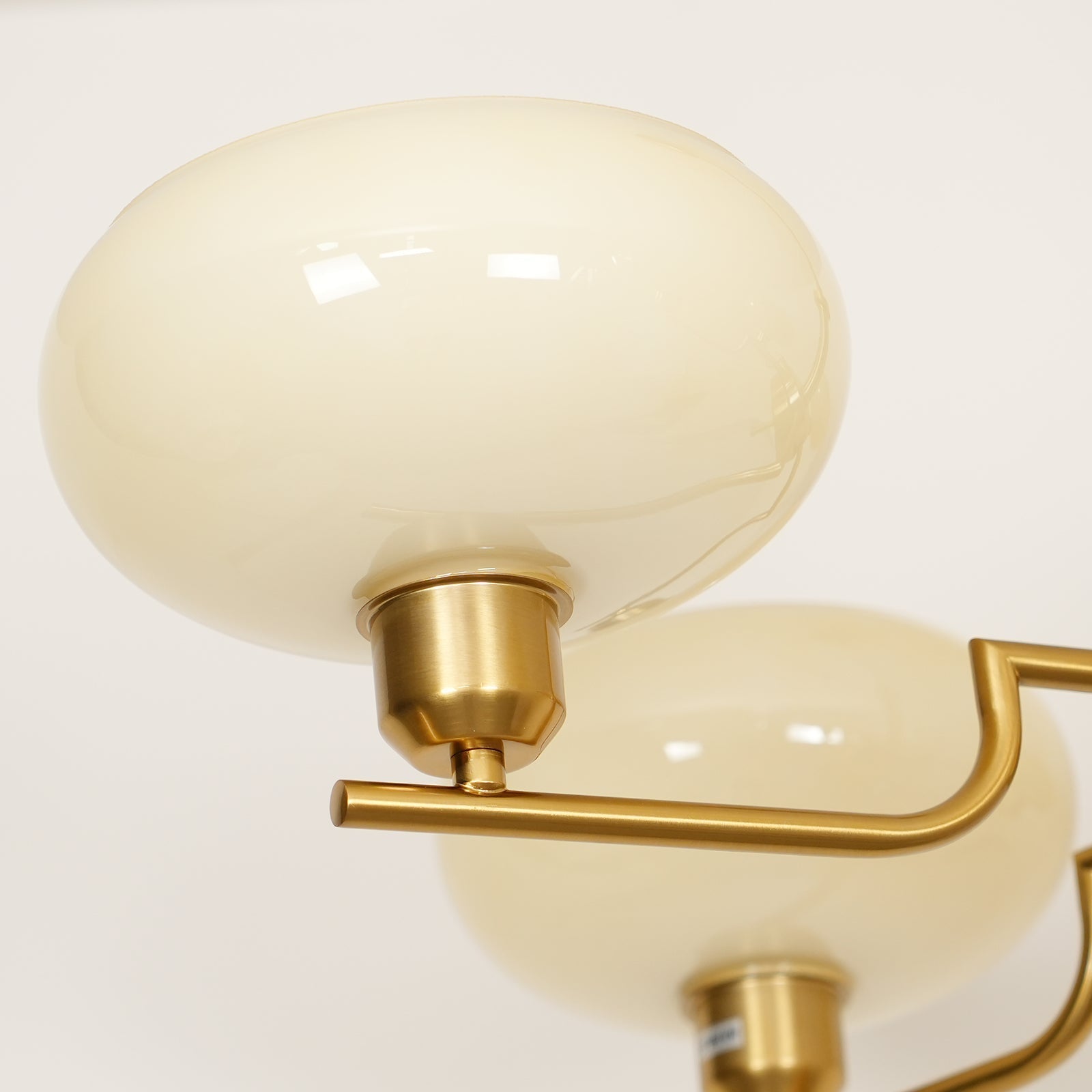 Close-up of a Clérachic cream glass globe on the copper cup fitting, a second shade behind it.