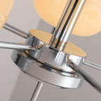 Detail of the Clérachic polished chrome centre hub and arms, lit cream globes glowing behind.