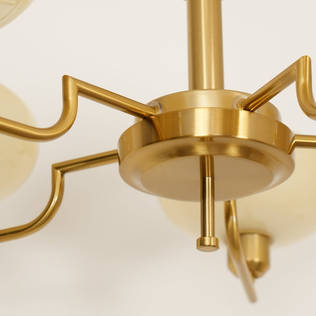 Underside of the Clérachic copper hub with stepped arms fanning out toward the cream glass globes.
