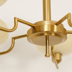 Underside of the Clérachic copper hub with stepped arms fanning out toward the cream glass globes.