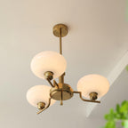 Clérachic three-head copper chandelier with white opal globes, viewed from below with a plant in front.