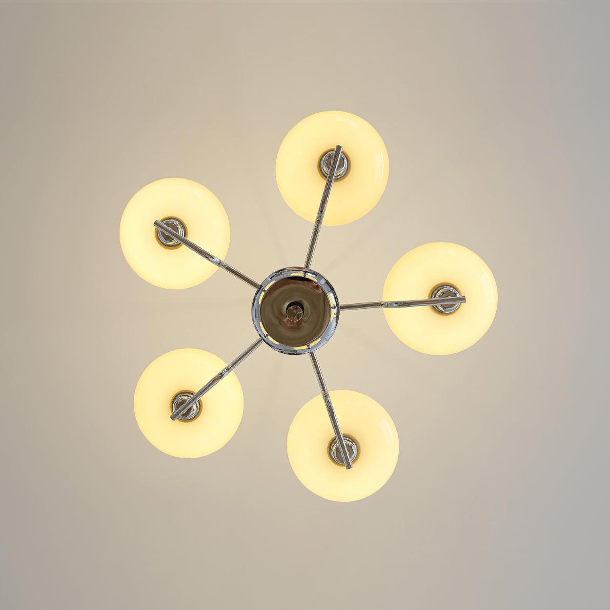 Clérachic five-head chrome chandelier from directly below, five cream globes glowing in a star pattern.