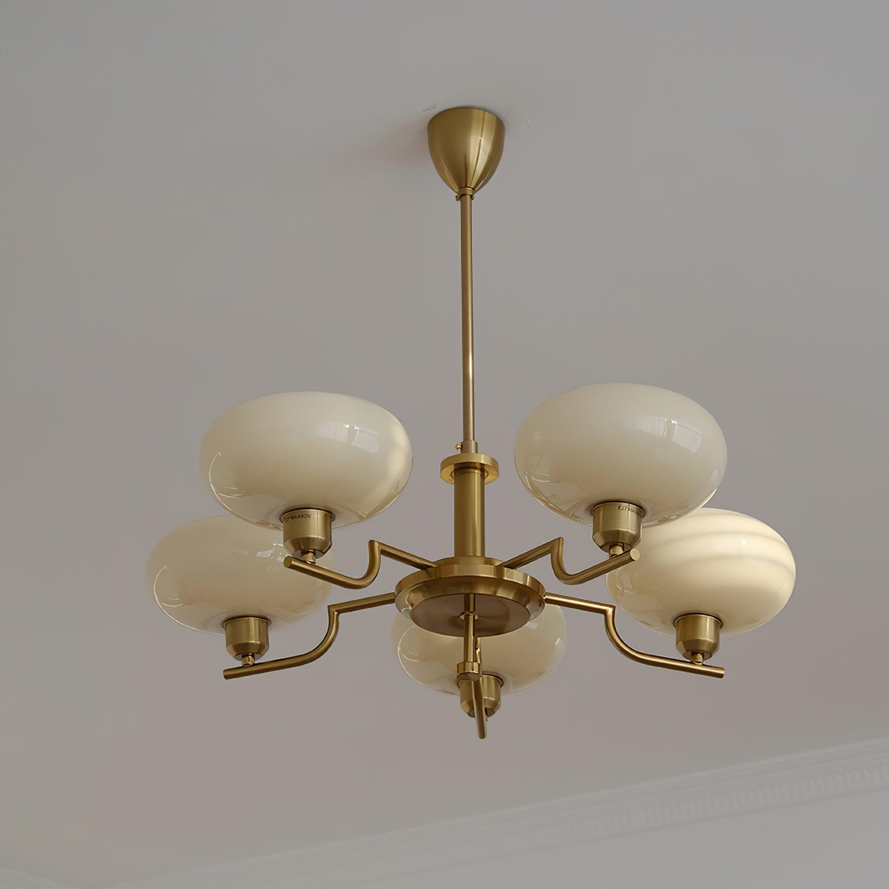 Clérachic five-head copper chandelier unlit, five white globes on stepped arms against a plain white ceiling.
