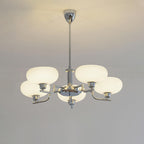 Clérachic five-head chrome chandelier lit warm, five flattened globes glowing above a moulded wall.