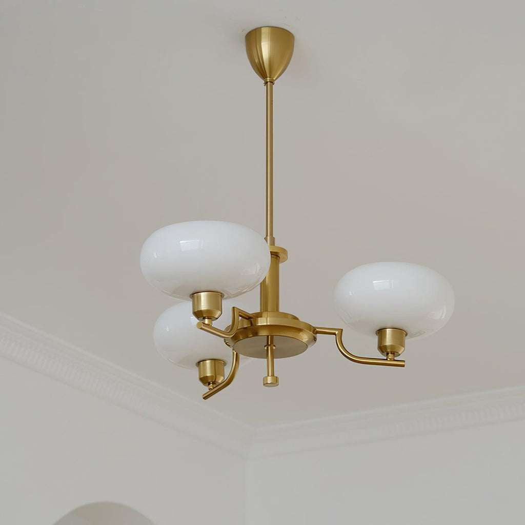 Clérachic three-head copper chandelier unlit, white flattened globes against a white ceiling and moulding.