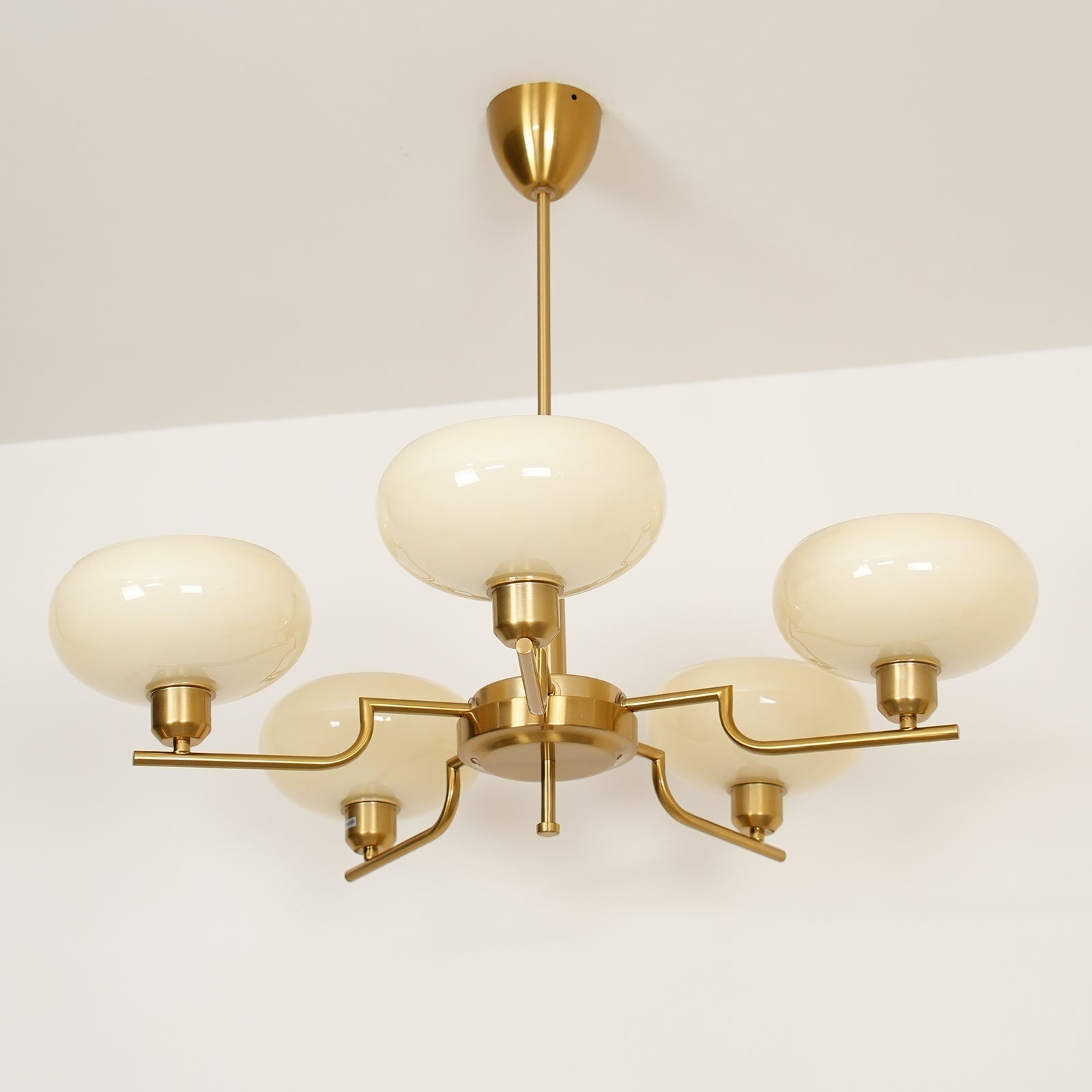 Clérachic five-head copper chandelier from above, centre globe plus four stepped arms on a white backdrop.