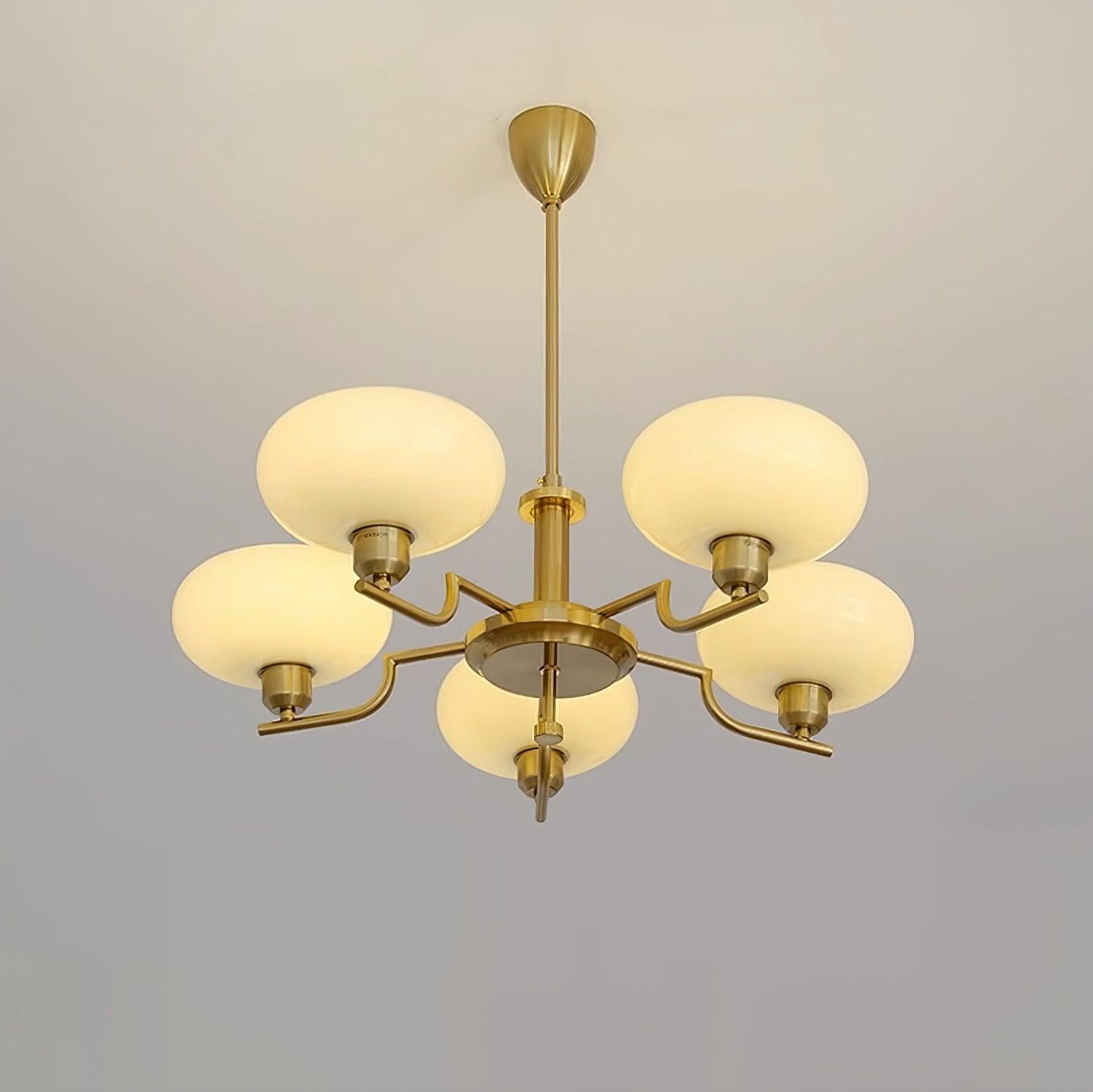 Clérachic five-head copper chandelier lit in studio, five glowing globes in a star on a pale grey wall.