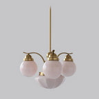A Clérachic copper-plated 4-light glass globe chandelier shows blush globes and a pink fluted bowl, studio view.