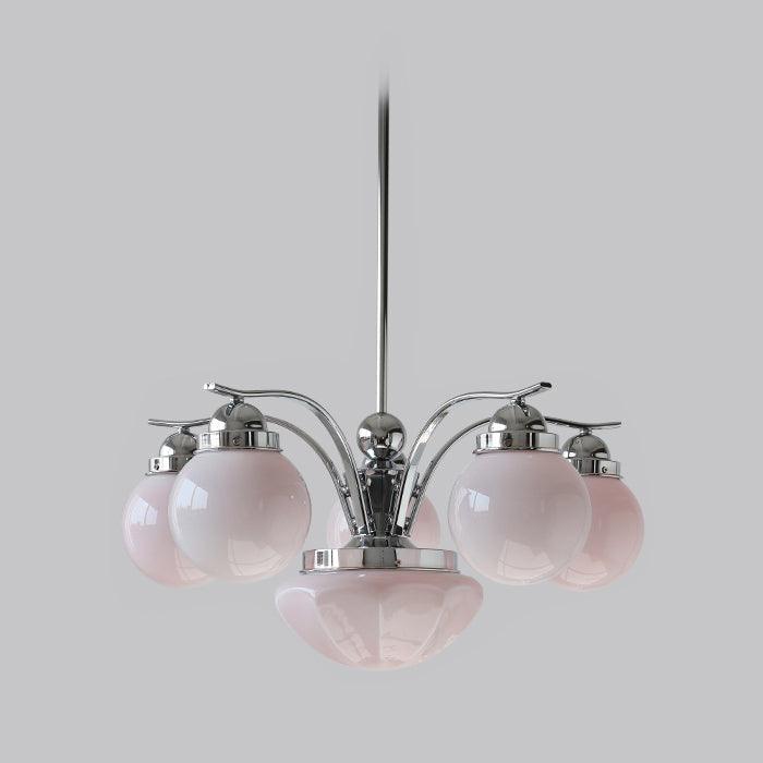 A Clérachic chrome 6-light glass globe chandelier hangs unlit, pale pink globes circling the lower bowl.