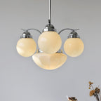 Clérachic chrome 4-light glass globe chandelier glowing warm above dried florals in the corner of the frame.