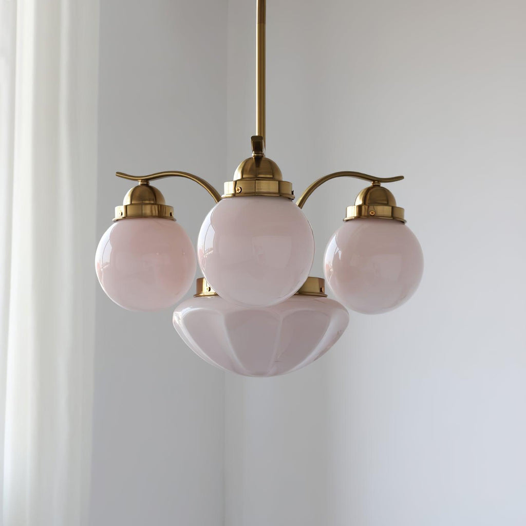 Clérachic 4-light glass globe chandelier in copper-plated metal hanging beside a sheer white curtain in a bright room.