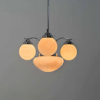 Clérachic chrome 4-light glass globe chandelier lit warm, three cream globes and a ribbed bowl on a grey backdrop.