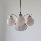 Clérachic chrome 4-light glass globe chandelier with pale pink globes and wavy decorative caps on the fittings.