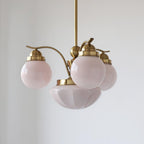 Clérachic copper-plated 4-light glass globe chandelier, blush-pink globes and a fluted bowl on an off-white wall.