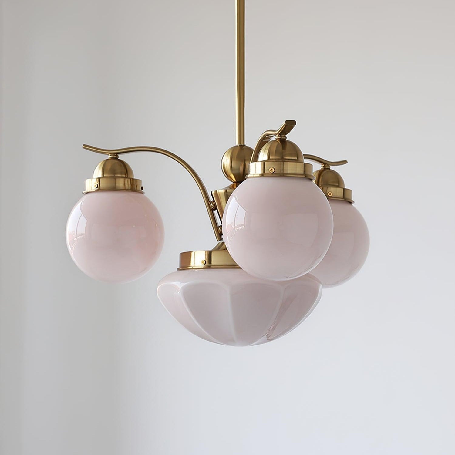 Clérachic copper-plated 4-light glass globe chandelier, blush-pink globes and a fluted bowl on an off-white wall.