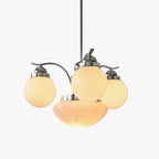 Clérachic chrome 4-light glass globe chandelier glowing amber-warm, cream globes and a fluted bowl on white.