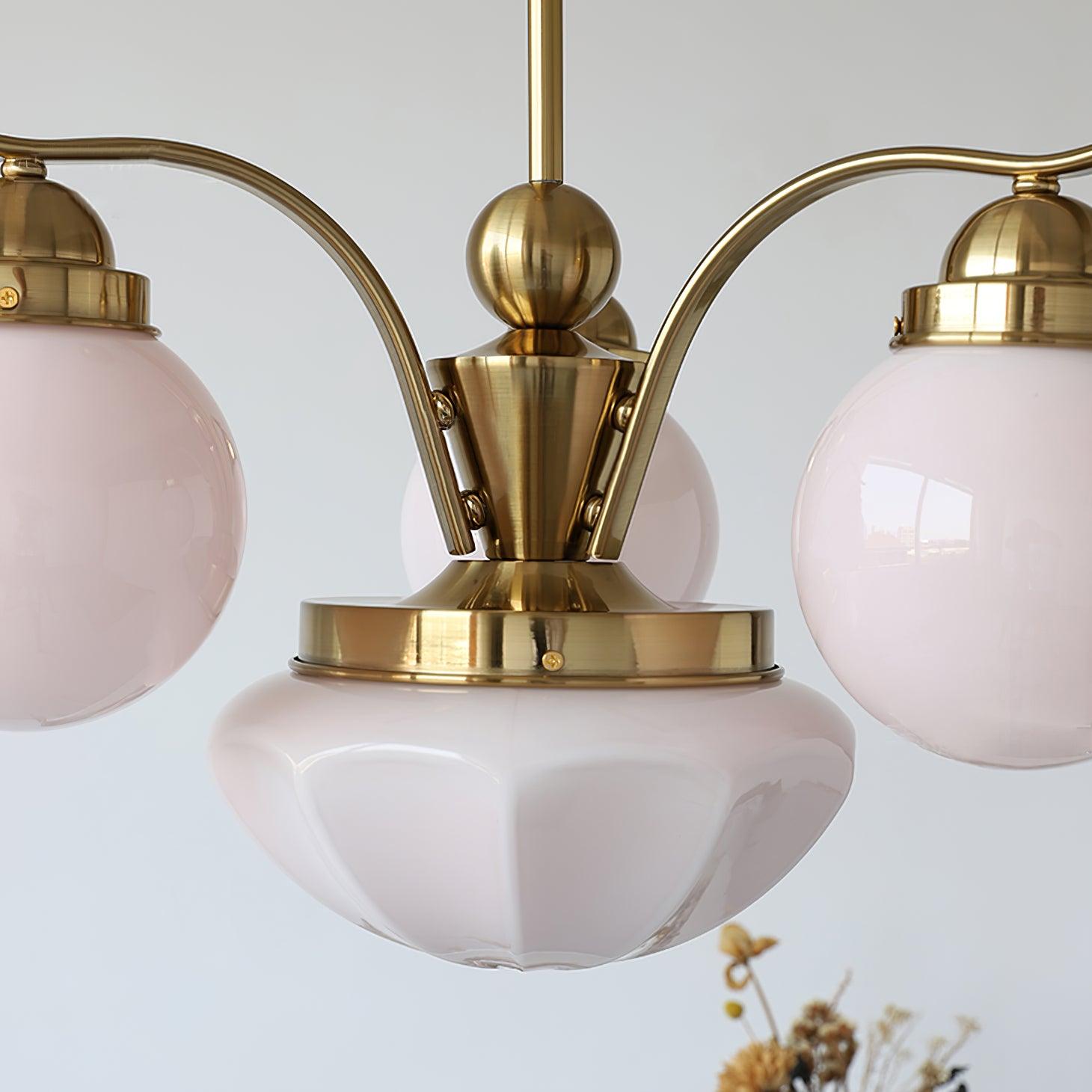 Close-up of the Clérachic copper-plated 4-light glass globe chandelier, pink globes and a fluted bowl beside dried flowers.