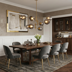 Smoky grey globes on a gold-finish Clérachic chandelier over a long walnut table, with a large gold-framed artwork behind.